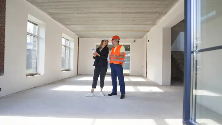 Client and site manager in a hi-vis vest walking through an empty finished interior