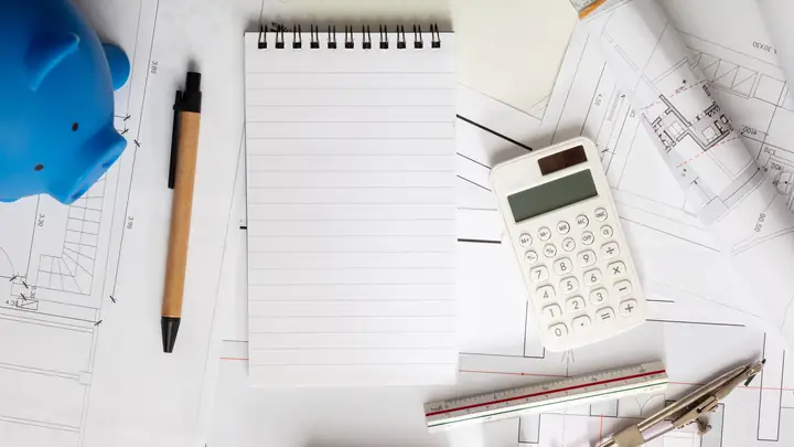 Notepad, pen, calculator and a blue piggy bank on drawings