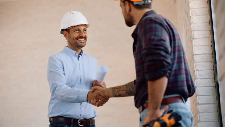 Client shaking hands with a tradesman holding a tool belt