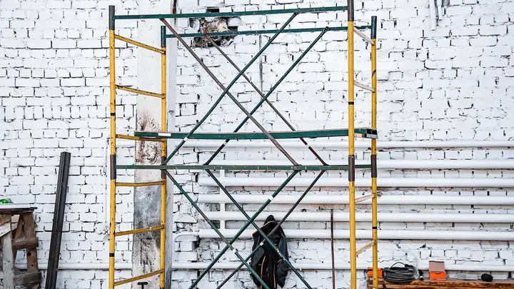 Scaffold tower against a white-painted brick wall