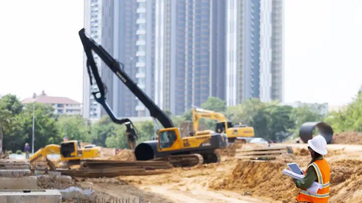 Excavators working on a large site with an engineer holding a tablet