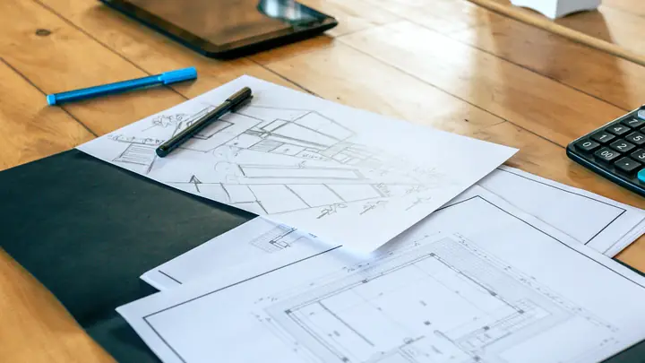 Calculator, folder and drawings on a wooden table