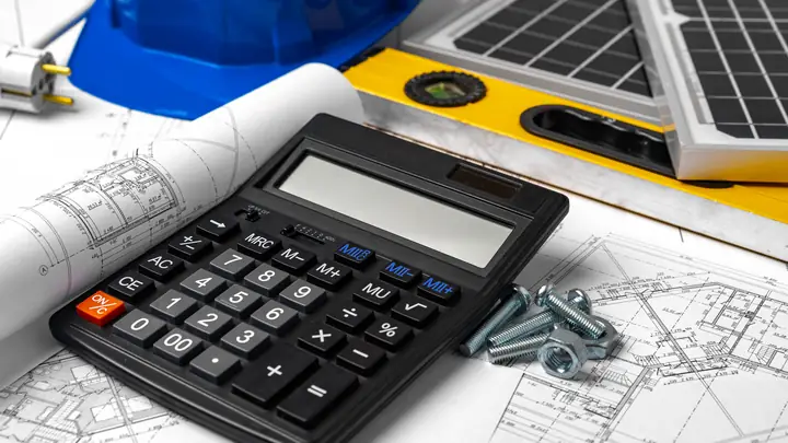 Calculator, bolts and a blue hard hat on a set of drawings