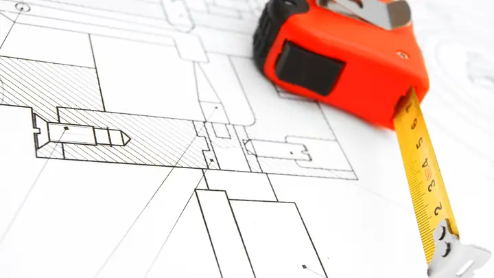 Orange tape measure lying on a technical drawing