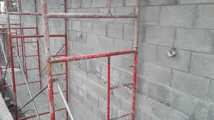 Scaffolding against a grey blockwork wall