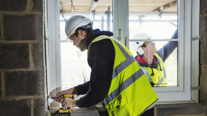 Worker in a hi-vis vest fitting a new window into a blockwork wall