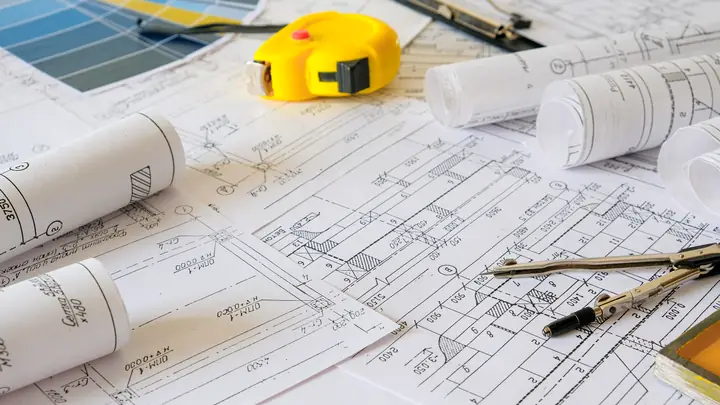 Rolled plans, tape measure, dividers and colour swatches on drawings