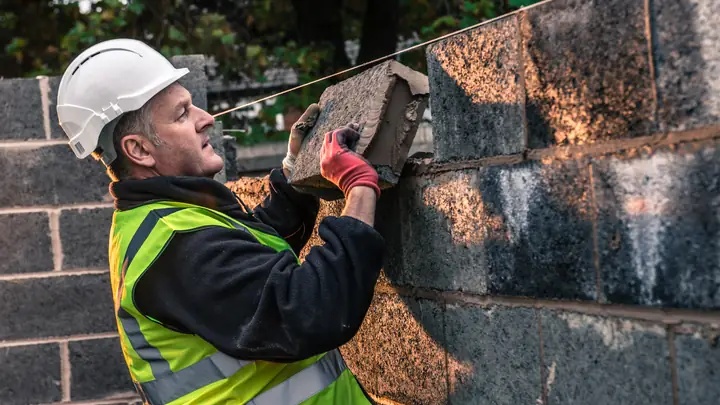Worker in hi-vis lifting a concrete block into a wall