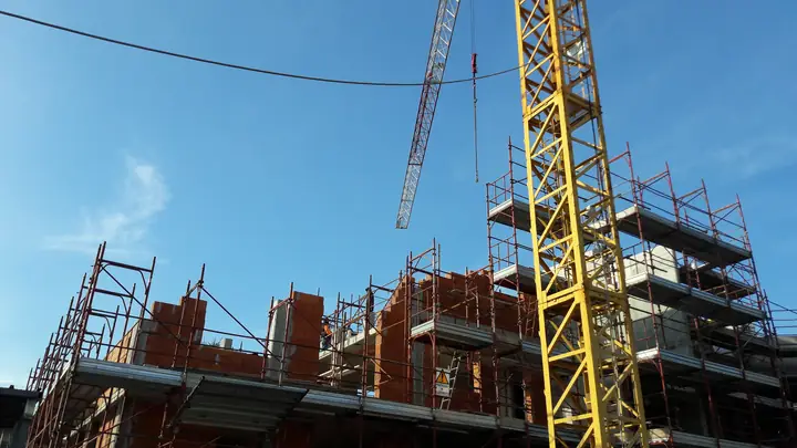 Tower crane and scaffolding around a brick building under construction