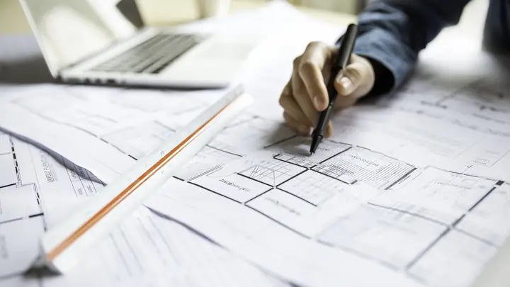 Hand drawing on a floor plan with a pen and ruler